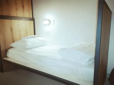 a bed with white sheets and pillows in a room at GARAGE HOSTEL in Nova Gorica