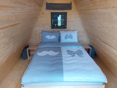 a bed in a cabin with a wooden wall at Glamping na podeželju in Lutverci