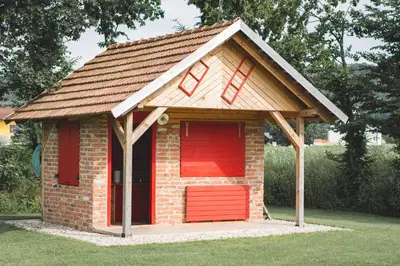 a small brick dog house with a red door at Glamping na podeželju in Lutverci