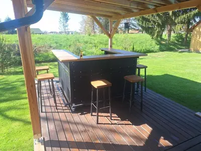 a bar on a wooden deck with stools at Glamping na podeželju in Lutverci