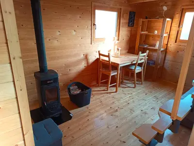 a dining room with a wood stove in a cabin at Jelenova lesena hiška in Loče pri Poljčanah