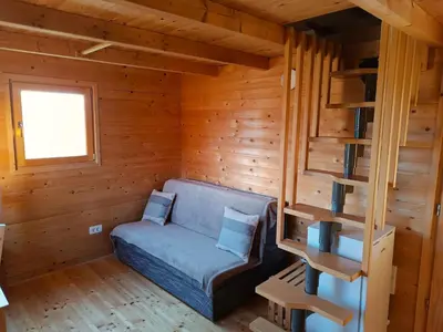 a room with a blue couch in a wooden room at Jelenova lesena hiška in Loče pri Poljčanah