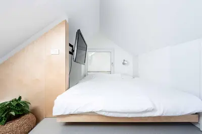 a white bedroom with a bed and a tv at Sheila's Loft in Ljubljana