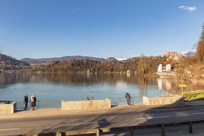 people standing on a sidewalk near a lake at Lakeview Bled Heaven Apartments in Bled