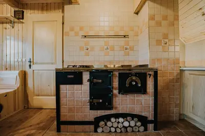a kitchen with an old fashioned stove in a room at Koča Kronca - Velika planina in Stahovica
