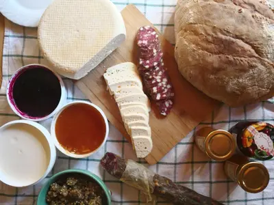 a table with bread and other ingredients on a cutting board at Koča Kronca - Velika planina in Stahovica