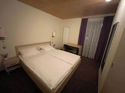a bedroom with a white bed and a window at Family Apartments Terme Topolšica - Pušpan in Topolšica