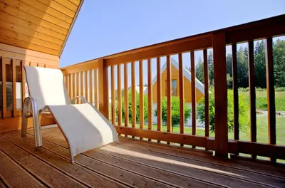 a porch with a white bench on a wooden deck at Family Apartments Terme Topolšica - Pušpan in Topolšica