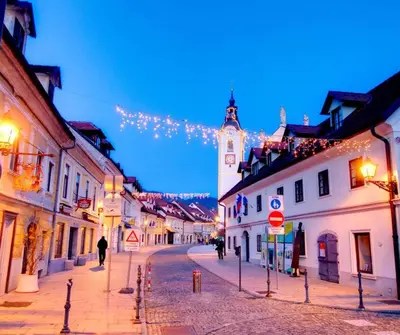 a city street at night with a clock tower at Apartment Kamnik-apartment with a large terrace in Kamnik