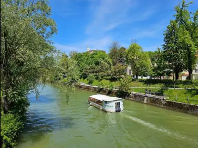 a boat traveling down a river with green water at Cozy Nest in Ljubljana