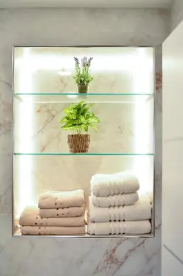 a glass shelf in a bathroom with towels and a plant at SEDAMI in Maribor