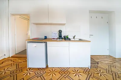 a kitchen with white cabinets and a wooden floor at P & B Apartment in Ljubljana
