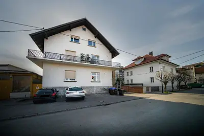a white house with two cars parked in front of it at P & B Apartment in Ljubljana