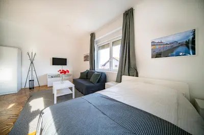 a bedroom with a bed and a couch and a window at P & B Apartment in Ljubljana