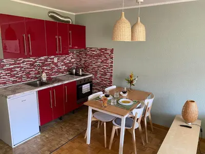a kitchen with red cabinets and a wooden table with chairs at Apartment Vita in Bovec