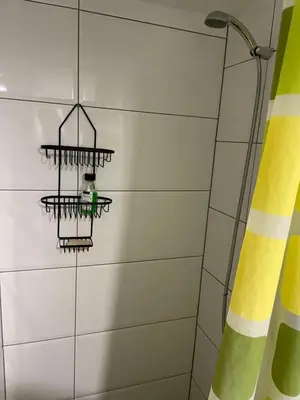a bathroom with a shower with a green and yellow curtain at Brasilia apartment in Ljubljana