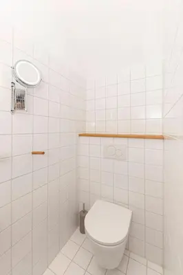 a white tiled bathroom with a toilet and a mirror at Apartma Jenkova rezidenca in Kranj