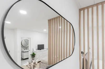 a mirror reflecting a room with a chair and a desk at Classy & Cozy apartment in Ljubljana