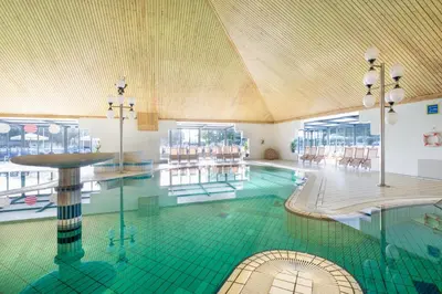 a swimming pool with a green tile floor in a building at Terme Banovci - Mobilne hiške Med Brajdami in Banovci