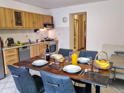 a kitchen with a wooden table with chairs and a dining room at Apartmaji Jakob 1 in Bovec
