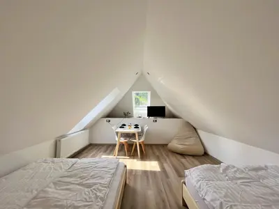 a bedroom with two beds and a desk in the attic at Hiša Grilc in Kranjska Gora