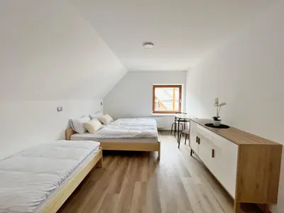 two beds in a room with white walls and wooden floors at Hiša Grilc in Kranjska Gora