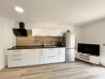 a kitchen with white cabinets and a stainless steel refrigerator at Hiša Grilc in Kranjska Gora