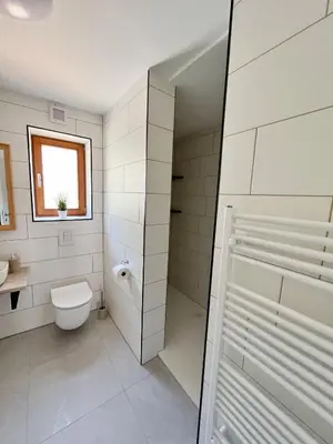 a white bathroom with a toilet and a window at Hiša Grilc in Kranjska Gora