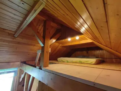 an attic room with a bed in a wooden cabin at Beehive cabin on a farm in Radovljica
