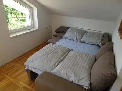 a bedroom with a bed and a couch and a window at Turistična kmetija Izgoršek in Griže