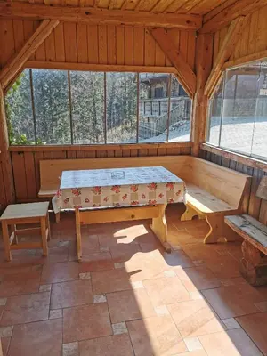 an empty room with a table and benches in a cabin at APARTMA BREST in Gornji Grad