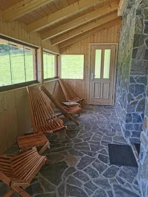 a room with rocking chairs and a stone wall at APARTMA BREST in Gornji Grad