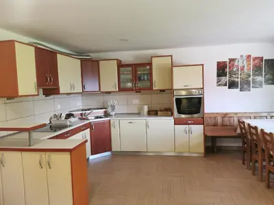 a large kitchen with white cabinets and a table at APARTMA BREST in Gornji Grad