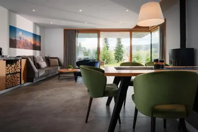 a living room with a table and green chairs at Ambient Resort Bled in Bled