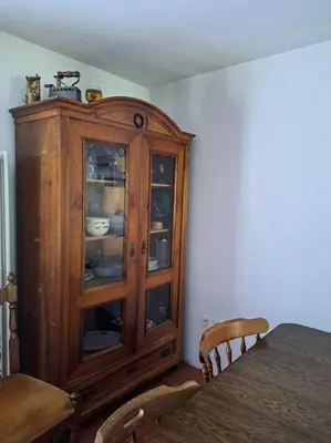 a wooden cabinet in a dining room with a table at Sanjska Hiša Vojsko in Idrija