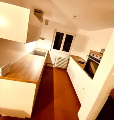 a kitchen with white cabinets and a wooden floor at Sanjska Hiša Vojsko in Idrija