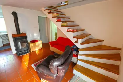 a living room with a staircase with a couch and a chair at Sanjska Hiša Vojsko in Idrija