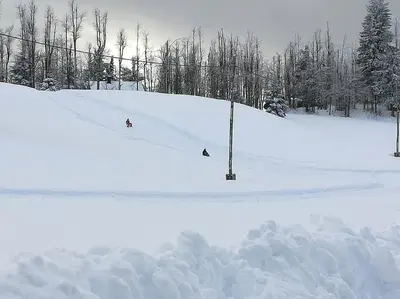 two people are skiing down a snow covered slope at Sanjska Hiša Vojsko in Idrija