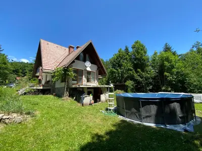 a house with a tarp on the grass in front of it at Sanjska Hiša Vojsko in Idrija