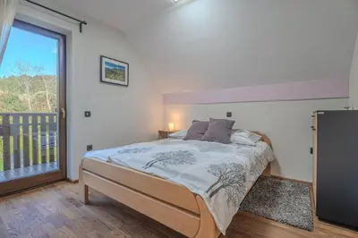 a bedroom with a bed and a large window at Resort Stari Malni, Osilnica - vacation houses Stari Malni in Osilnica