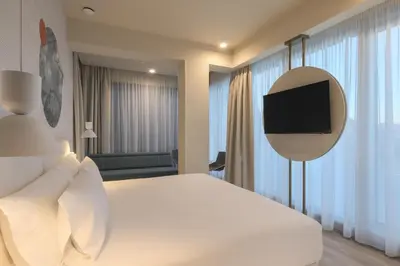 a bedroom with a white bed and a tv on a wall at Occidental Ljubljana in Ljubljana