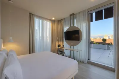 a white bedroom with a large bed and a mirror at Occidental Ljubljana in Ljubljana