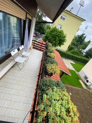 a patio with two white chairs and some plants at Apartma Magnolija in Nova Gorica