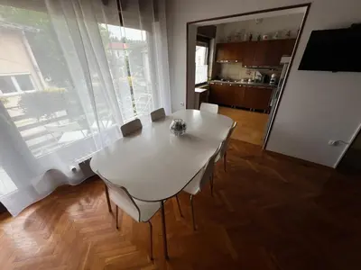 a white dining room table with chairs and a large window at Apartma Magnolija in Nova Gorica