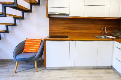 a kitchen with a chair with an orange pillow on it at The Happy Loft in Ljubljana