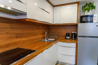 a kitchen with white cabinets and a stainless steel refrigerator at The Happy Loft in Ljubljana