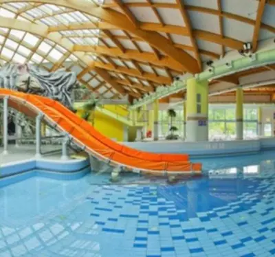 an indoor swimming pool with an orange slide in a building at Lotty in Čatež ob Savi