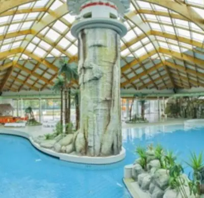a large swimming pool with a water slide in a building at Lotty in Čatež ob Savi