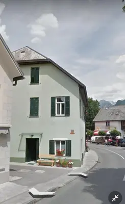 a white house with green shutters on a street at Belavita in Bovec