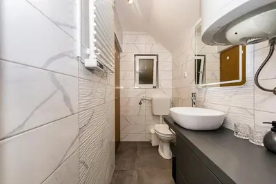 a white bathroom with a sink and a toilet at Cottage near river Kolpa, vineyards,top location. in Adlešiči